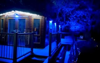Static home with composite decking surrounding it at night with blue lights