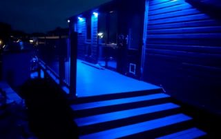 Static home with composite decking surrounding it at night with blue lights