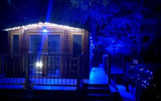 Static home with composite decking surrounding it at night with blue lights