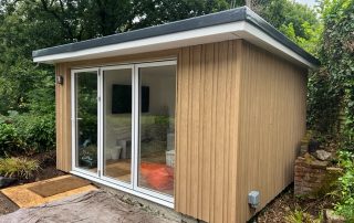 Millboard board and batten cladding installed on the exterior of a yoga room that has patio doors in a garden