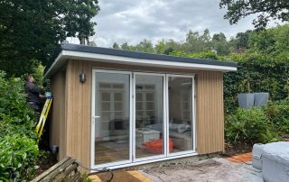 Millboard board and batten cladding installed on the exterior of a yoga room that has patio doors in a garden