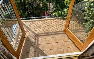 Doors opening onto a balcony created using Millboard composite decking in Golden Oak - a brown colour.