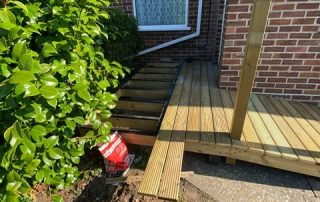 Work in progress installing a ramp with grip strips and decking with a railing created from timber surrounding a corner of a residential property