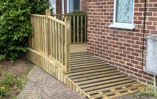 Ramp with grip strips and decking with a railing created from timber surrounding a corner of a residential property