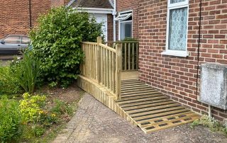 Ramp with grip strips and decking with a railing created from timber surrounding a corner of a residential property