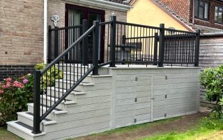 Steps leading down to the back garden from the back door of a property created using Millboard's smoked oak decking - a light grey colour