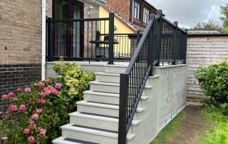 Steps leading down to the back garden from the back door of a property created using Millboard's smoked oak decking with a black railing