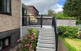 Steps leading down to the back garden from the back door of a property created using Millboard's smoked oak decking with a black railing