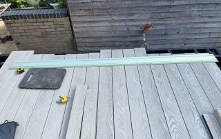 Work in progress building steps leading down to the back garden from the back door of a property created using Millboard's smoked oak decking with a black railing