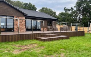 Millboard Composite Decking in Antique Oak Waterlooville 6 Far view shot centred on the stairs of a large composite decking porch installed to a house in Waterlooville
