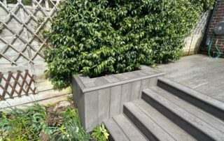 Millboard Composite Decking in Ebony Grey – Arundel, West Sussex 4 Composite decking stairs installed forming stairs off of the porch in a garden in Arundel
